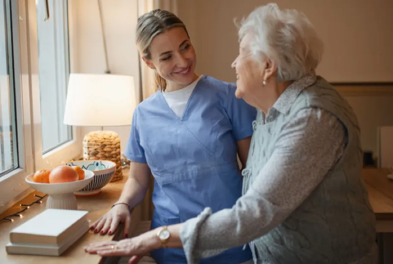 A companion and an older woman chatting warmly at home