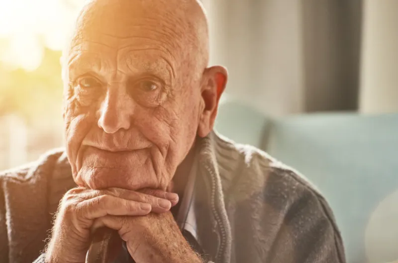 An older man sitting thoughtfully at home